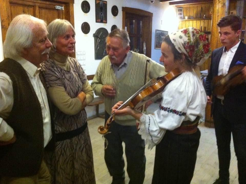 Young violinists performing traditional folk music for guests at an art exhibition.