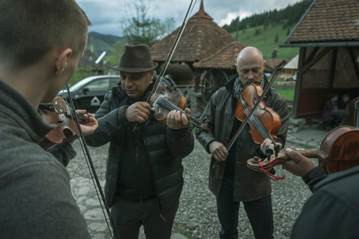 Folk musicians playing violins together outside the heritage buildings.