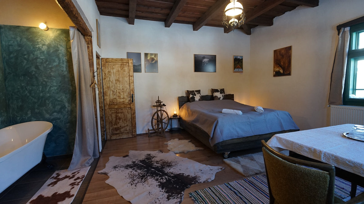 Bedroom with a cowhide rug, a decorative spinning wheel, and a dining table set near the bed.