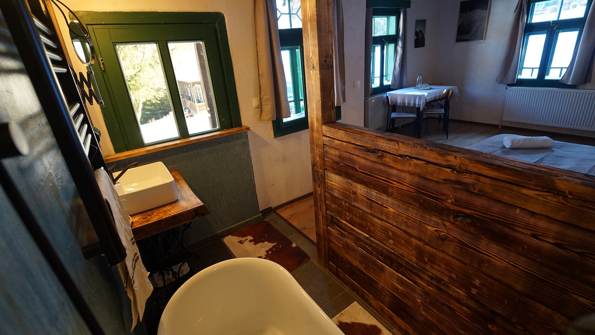 Ensuite bathroom with a freestanding tub and vessel sink, separated from the bedroom by a rustic wood partition.
