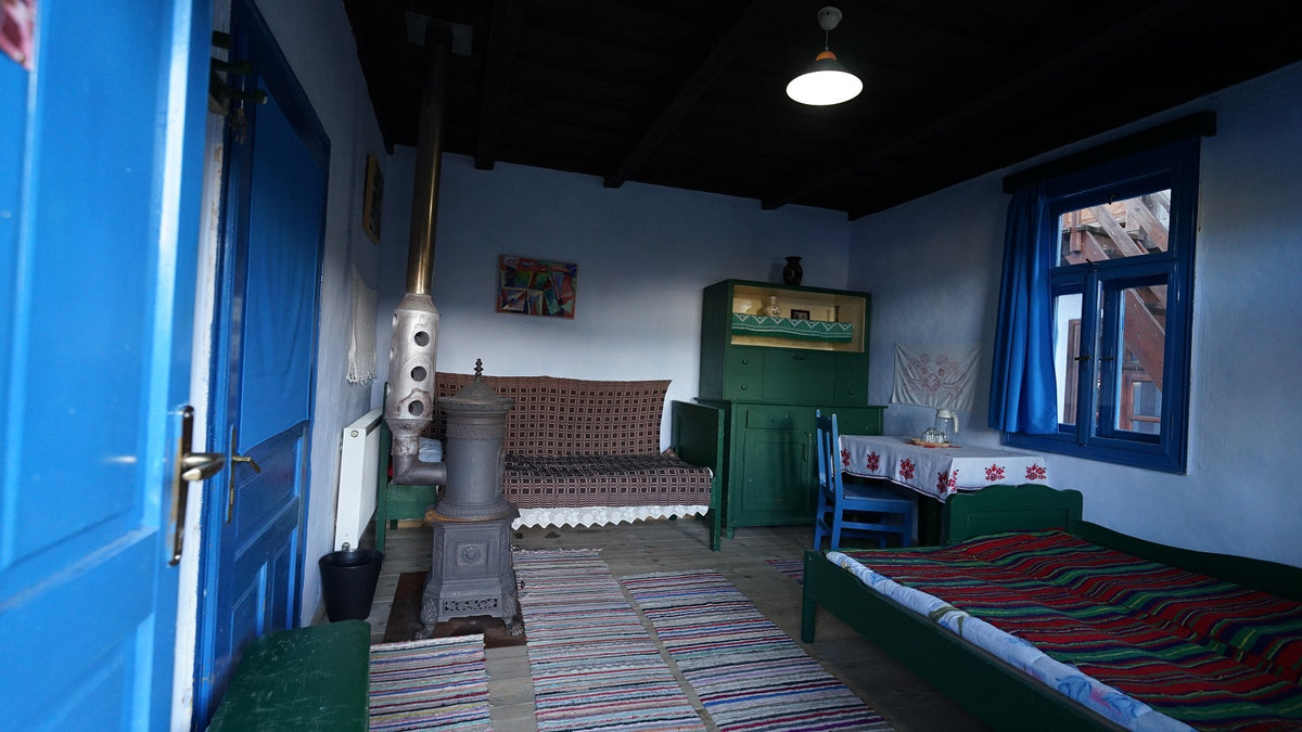 Room with a decorative cast-iron tile stove, a green cabinet, and striped rag rugs on the floor.