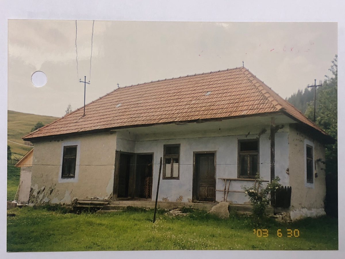 Archival photo of the Bálványos house in June 2003, showing peeling plaster and worn doors before restoration.
