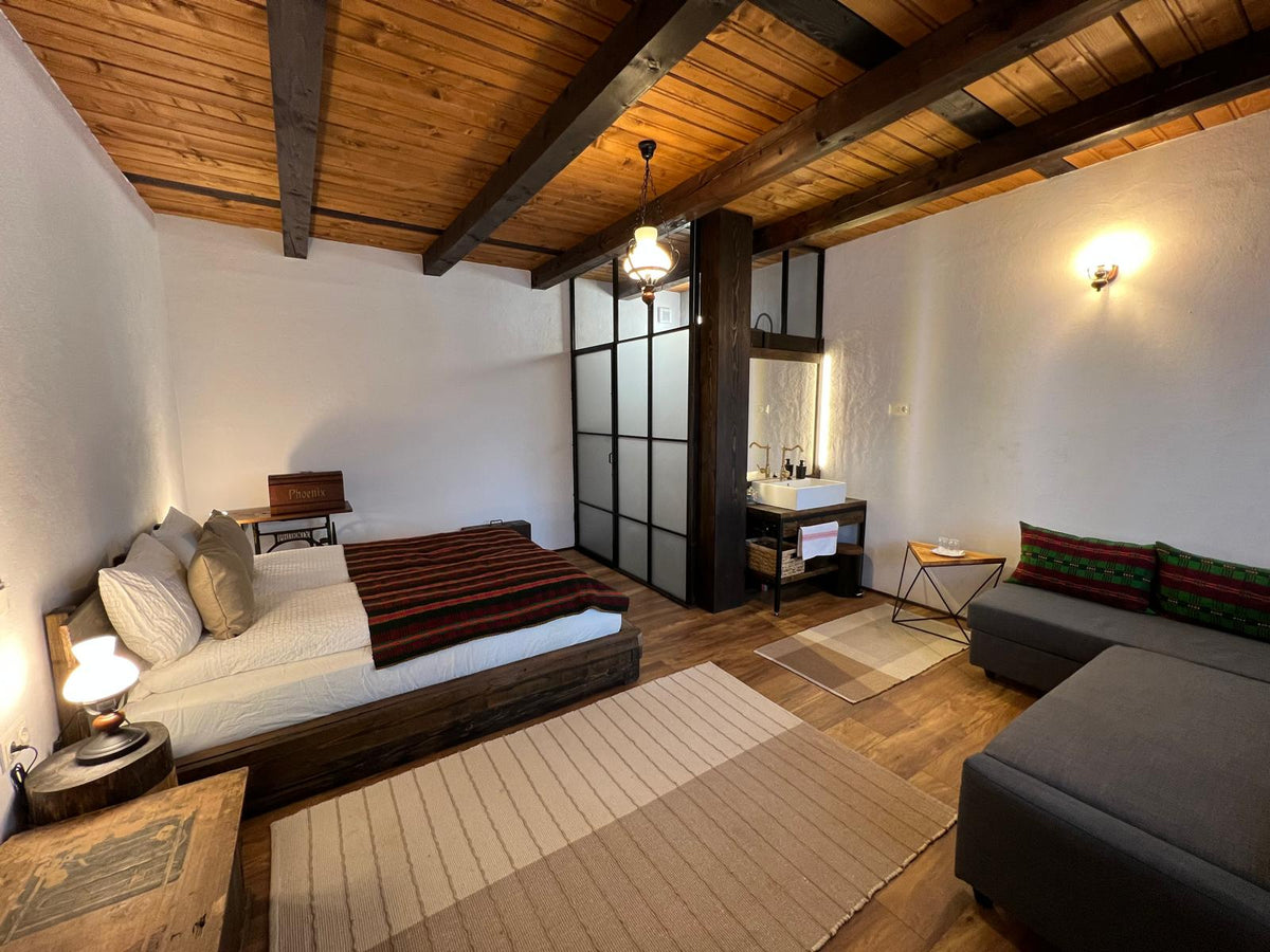Suite with a low platform bed, a repurposed antique sewing-machine table, and a glass-walled vanity nook.