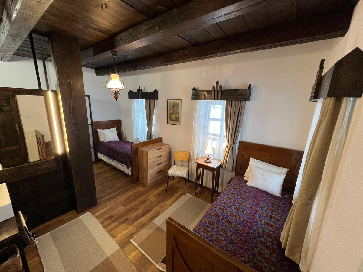 Twin beds in purple folk-pattern covers with dark wood headboards, a dresser set between them.