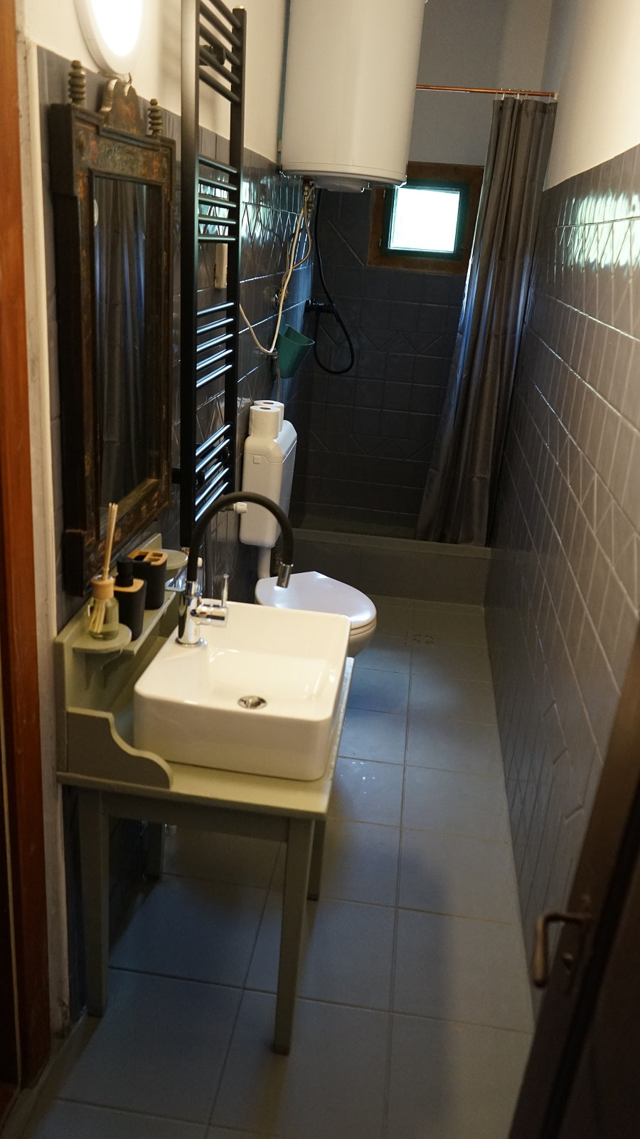 Bathroom with a vessel sink, an antique framed mirror, and a tiled shower area at the far end.