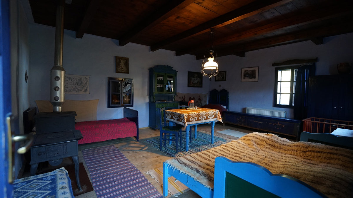 Room with an antique cast-iron stove, blue painted furniture, and a mustard striped bed throw.