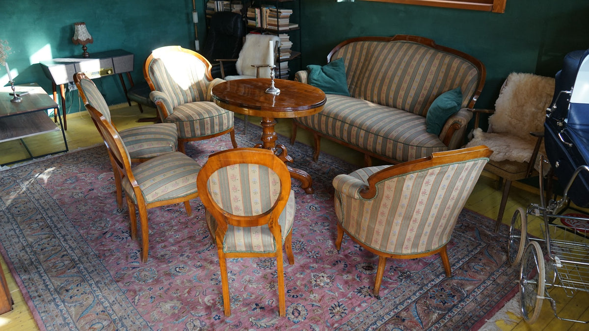 Antique striped parlor seating set around a round pedestal table, on a pink floral rug.