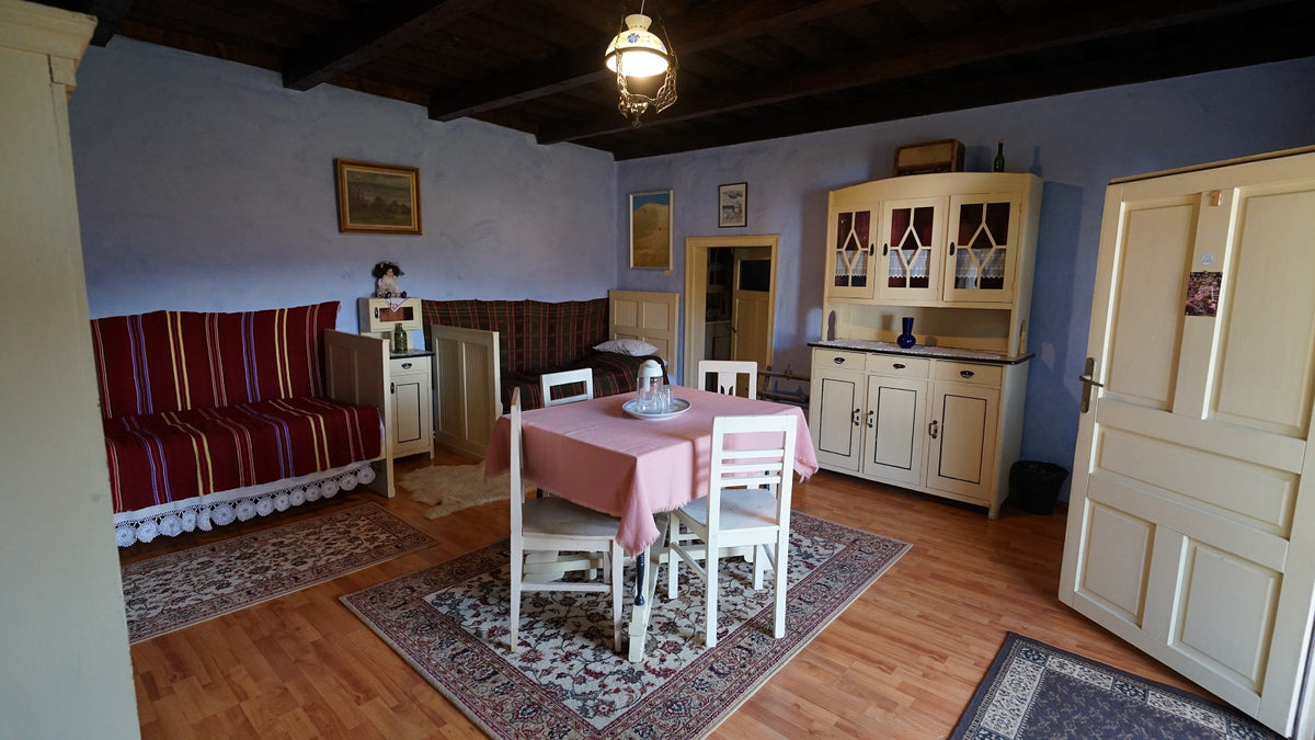 Sitting room with maroon striped bench seating, a pink-clothed dining table, and a cream glass-front cabinet.