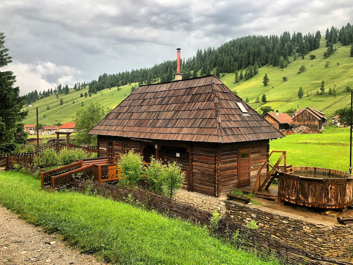 Overcast view of the building with the wooden tub on its deck and rooftops of the village in the distance.