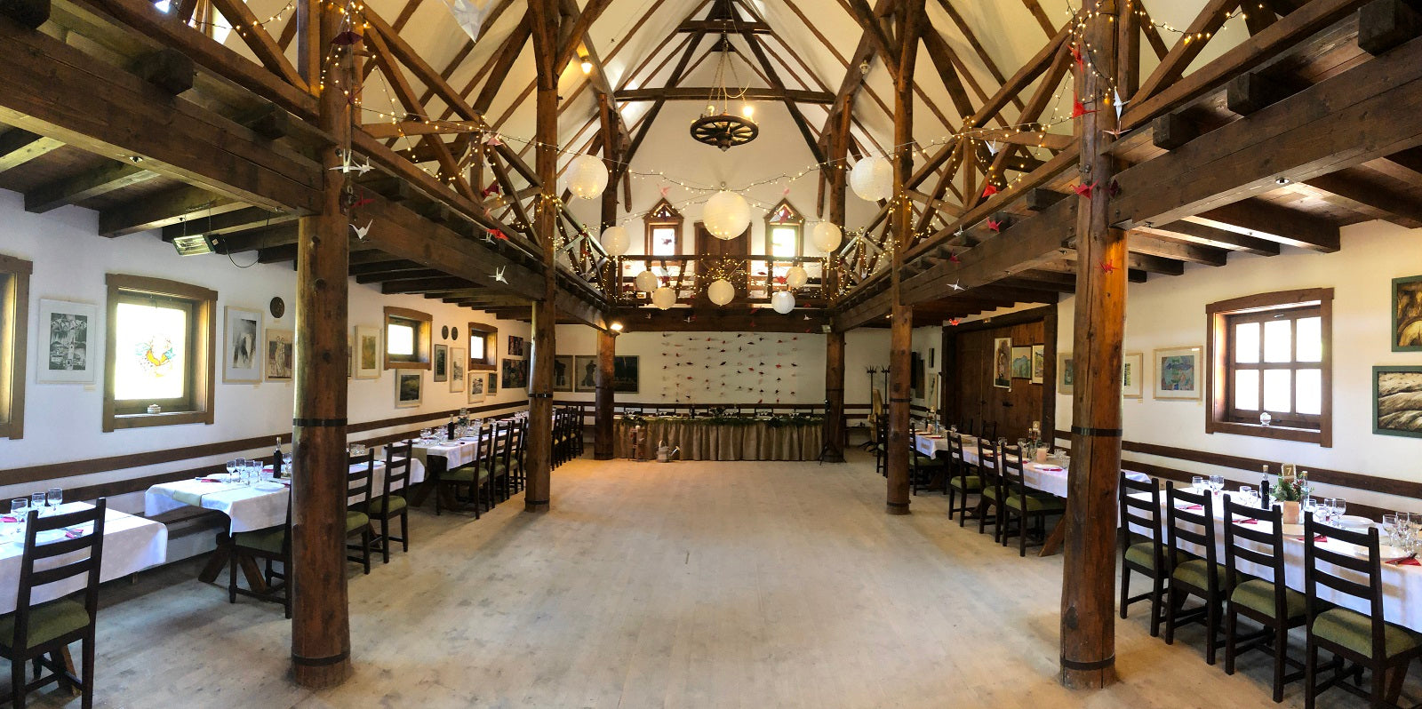 Barn set up for an event with paper lanterns, origami cranes, and tables draped with burlap along the mezzanine railing.