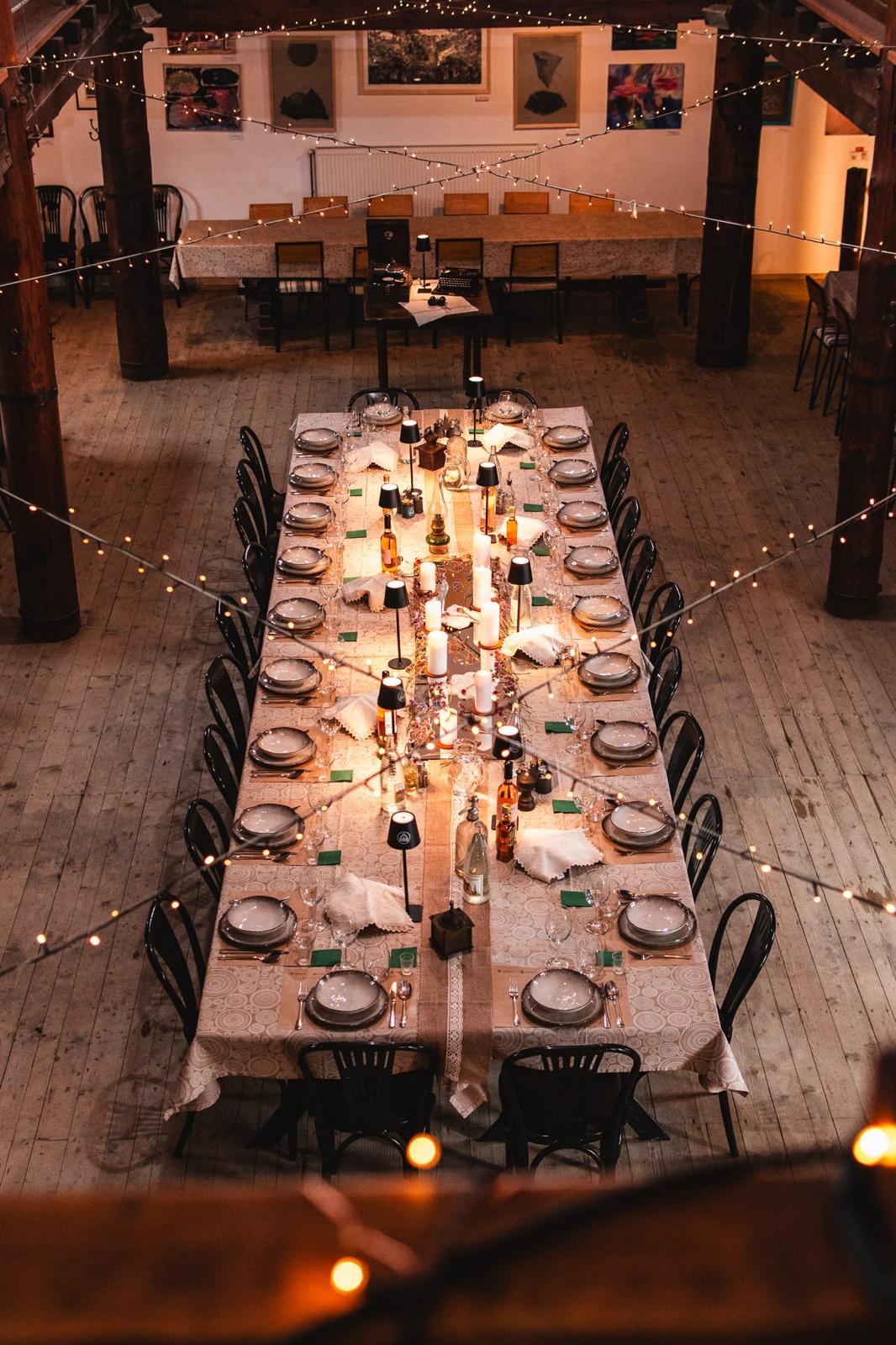 Candlelit banquet table set with fine china and glassware, viewed from the mezzanine above the barn's dance floor.