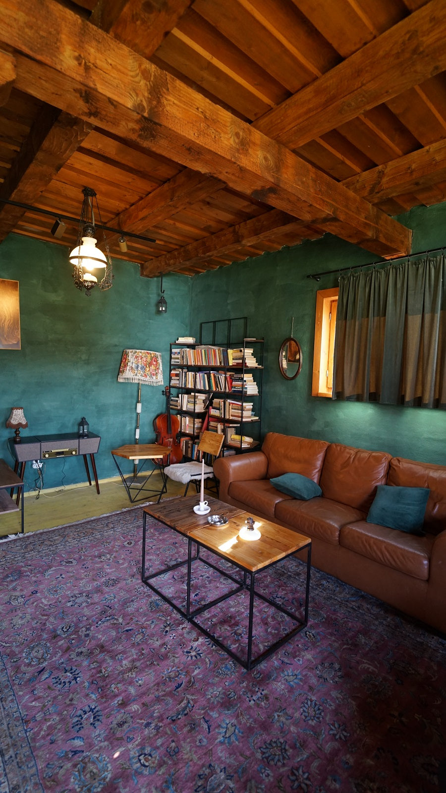 Lounge with a brown leather sofa, a cello beside a bookshelf, and a retro record player on a console table.