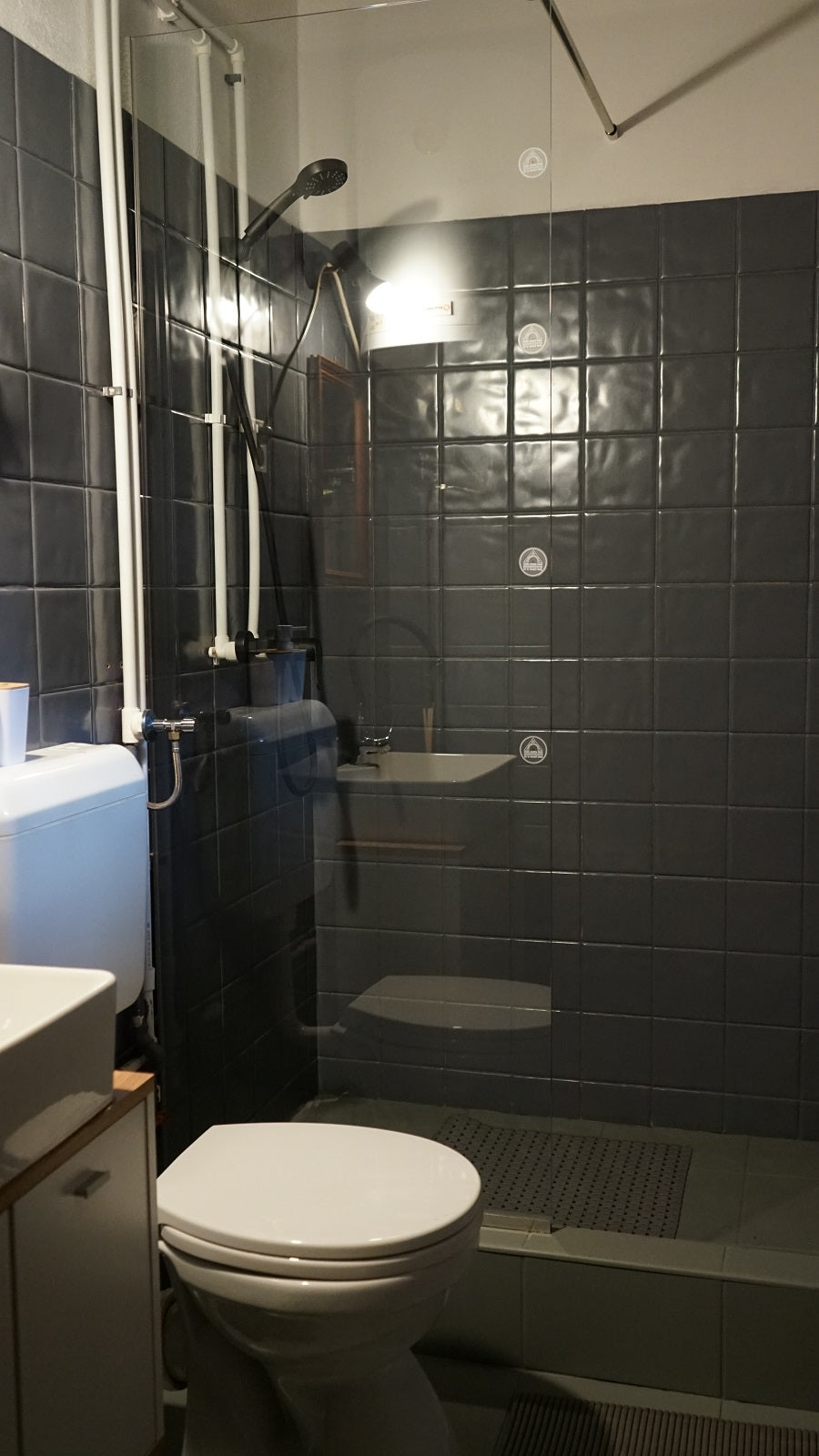 Bathroom with dark gray tile and a glass-walled walk-in shower.